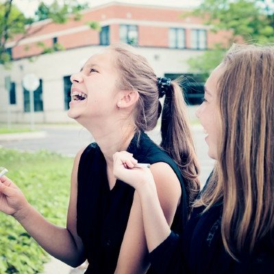 Young girls inhaling vape in park.